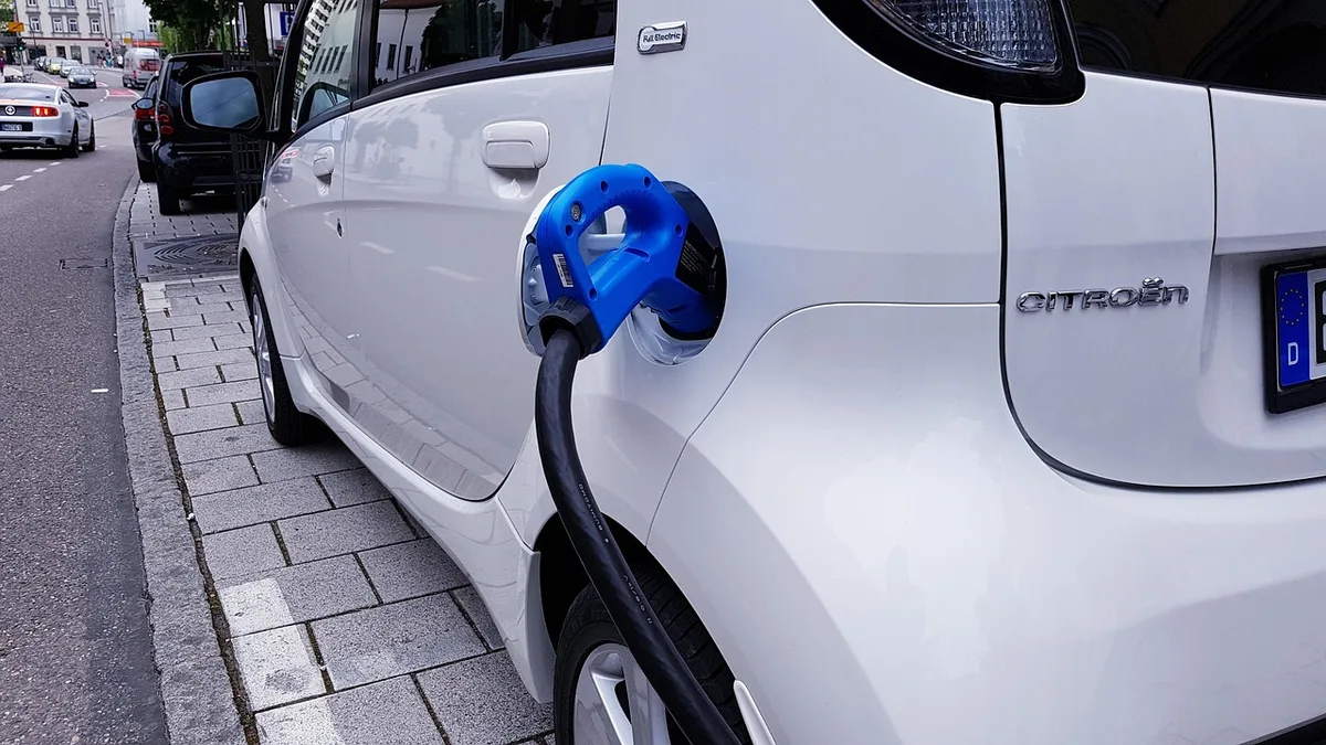 Personne connectant un chargeur à une batterie de vélo électrique dans un garage