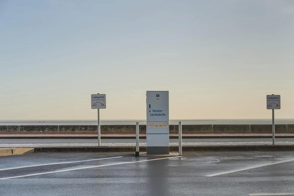 Vélo électrique appuyé, batterie amovible sur table et main branchant le chargeur