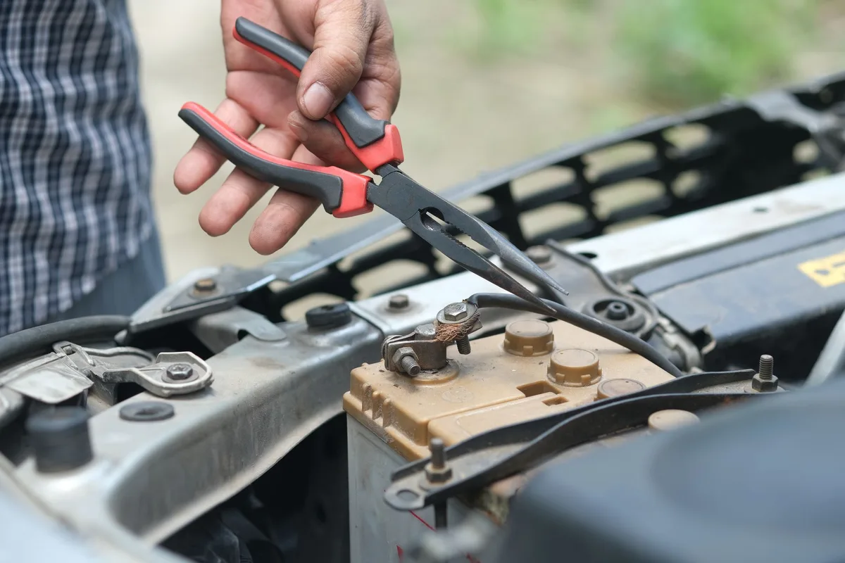 Batterie de vélo électrique posée sur une table d'atelier avec mains gantées et chargeur