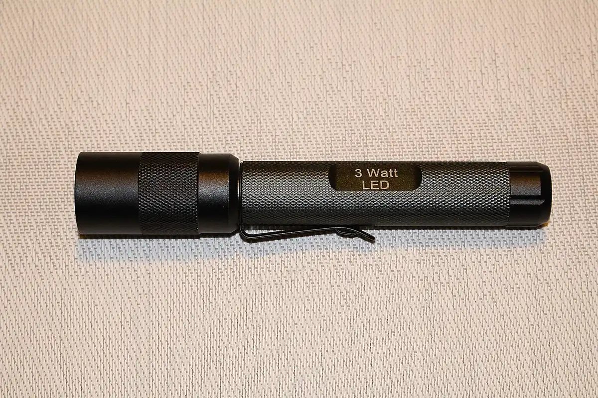 Main vérifiant l'indicateur de charge d'une batterie de vélo électrique sur un établi