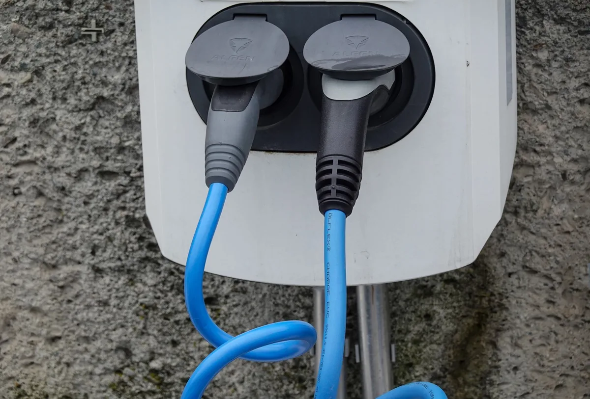 Batterie de vélo électrique sur cadre avec main branchant un chargeur dans un garage propre