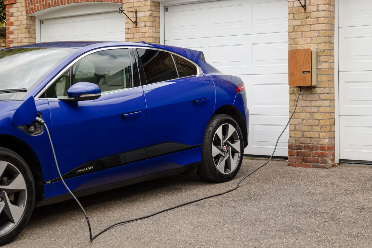 Batterie de vélo électrique et chargeur posés sur une table d'atelier, mains en arrière-plan